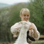 Joyful moment of a woman playing with a goat on a rural farm setting.